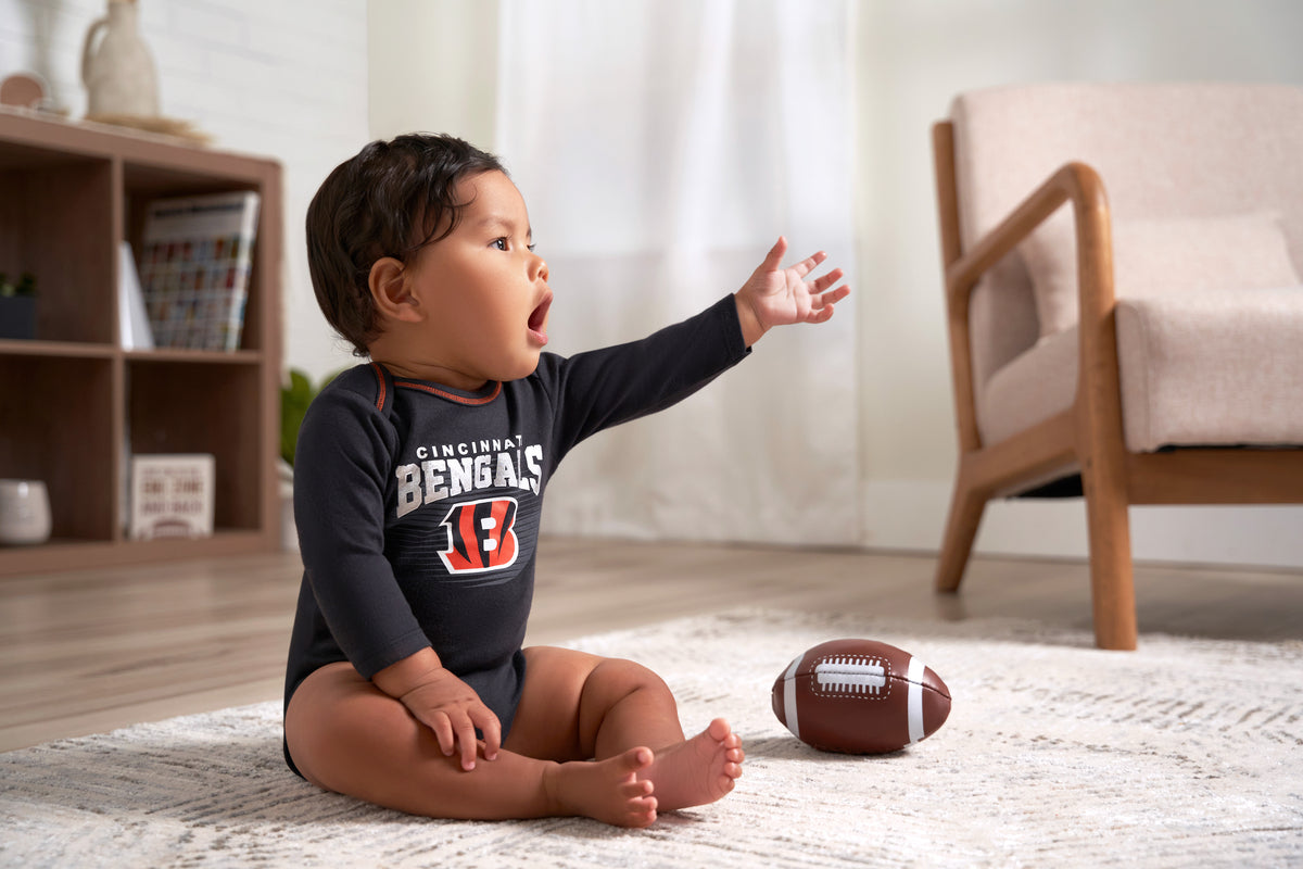 Look at this cute little one! They're dressed in a Bengals onesuit and having fun with a football. 