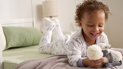 A young child laying on a bed with a stuffed animal