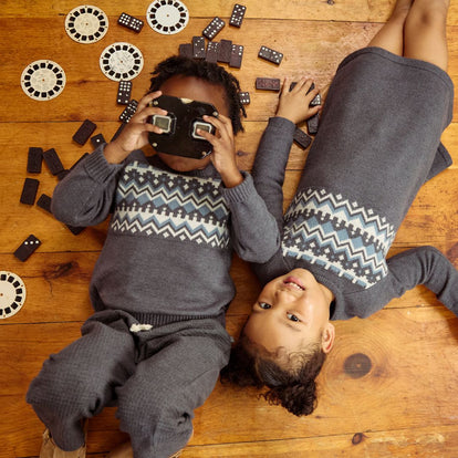  Two children in colorful sweaters are comfortably lying on the floor, enjoying a moment of relaxation together