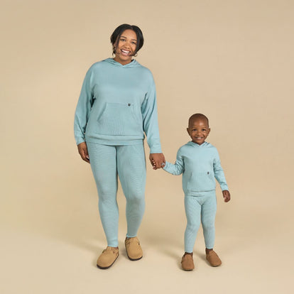  A woman and a child are dressed in matching blue sweatsuits, showcasing a coordinated and stylish look together