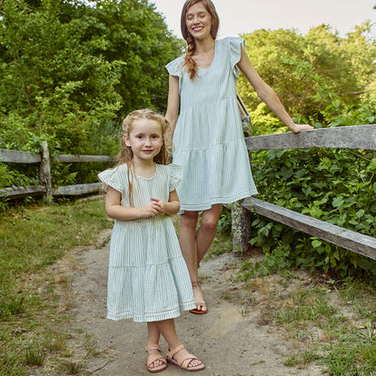  A mother and daughter wear matching Gerber Childrenswear® green gingham dresses while enjoying a peaceful spring day outdoors.